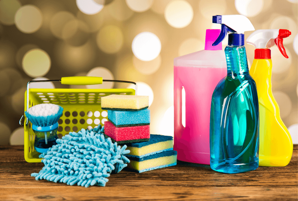 A collection of cleaning supplies on a wooden surface with a bokeh background