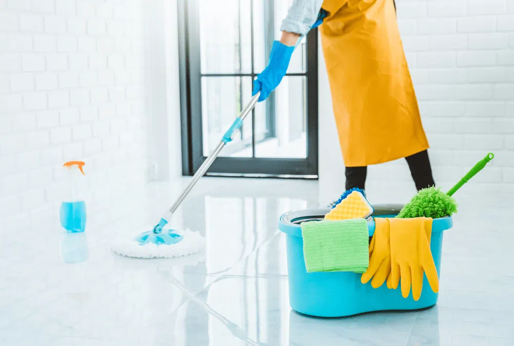 A person cleaning the floor with a mop in a bright room.